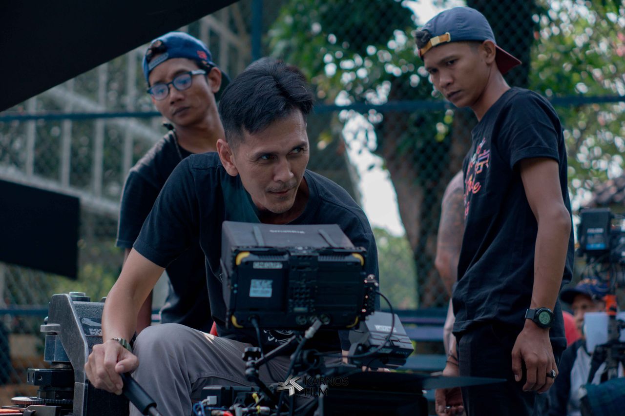 Group of filmmakers reviewing footage on set outdoors, focused on camera equipment.