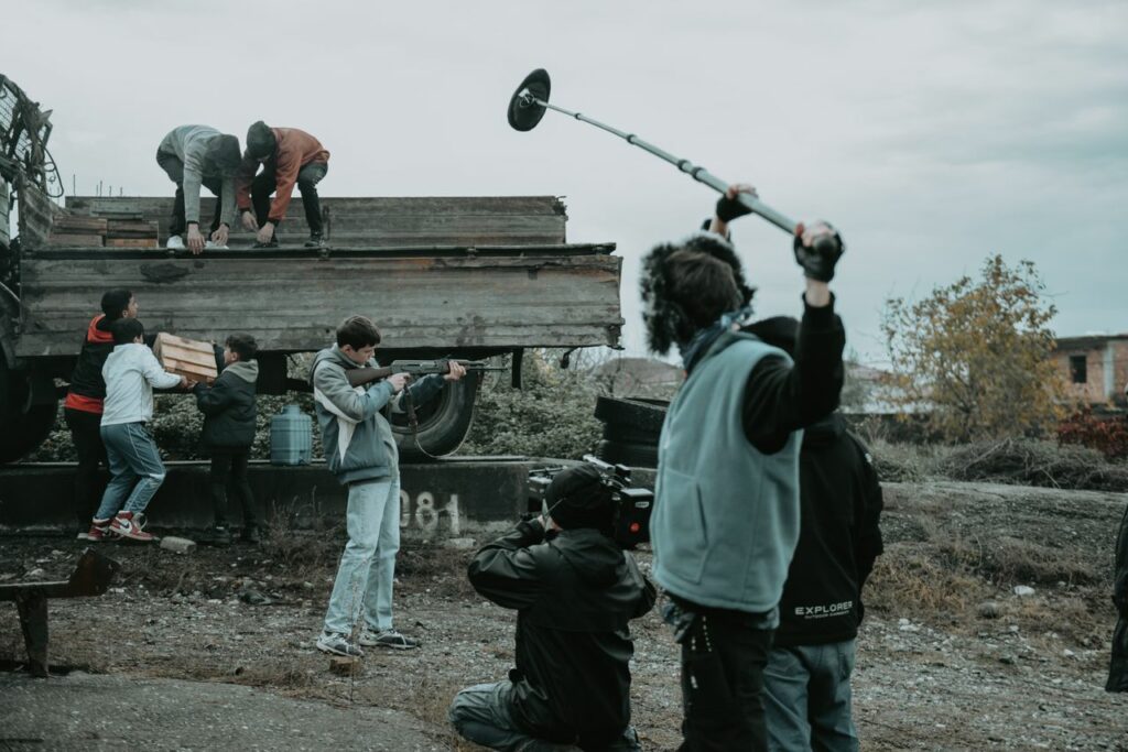 Crafting Captivating Headlines: Your awesome post title goes here Film crew working outdoors, capturing scenes with camera and boom mic.